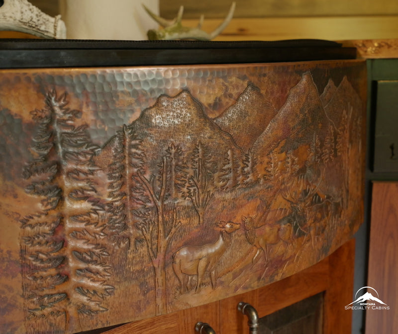 A hand-hammered copper sink featuring a Montana mountain and elk scene.