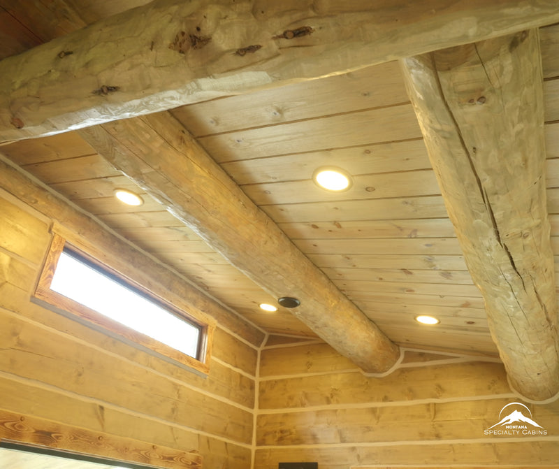 Exposed log beams and warm recessed lighting overhead.