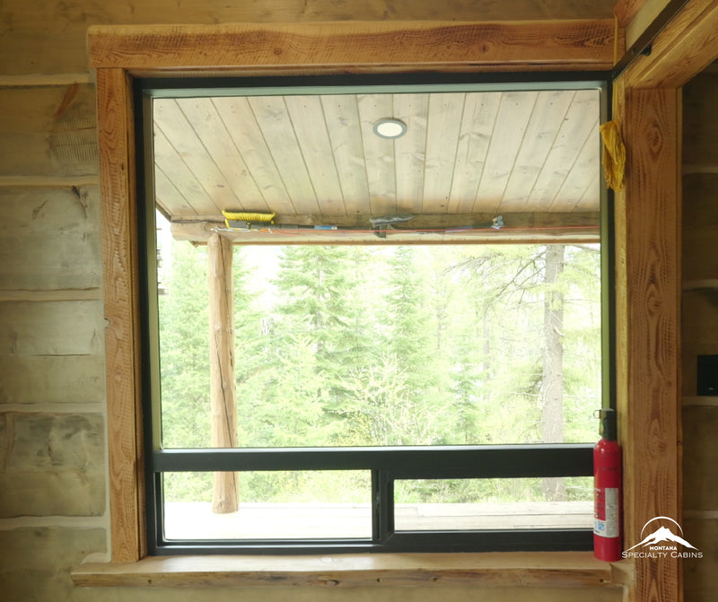 Large picture windows framed in rough-sawn timber for forest views.
